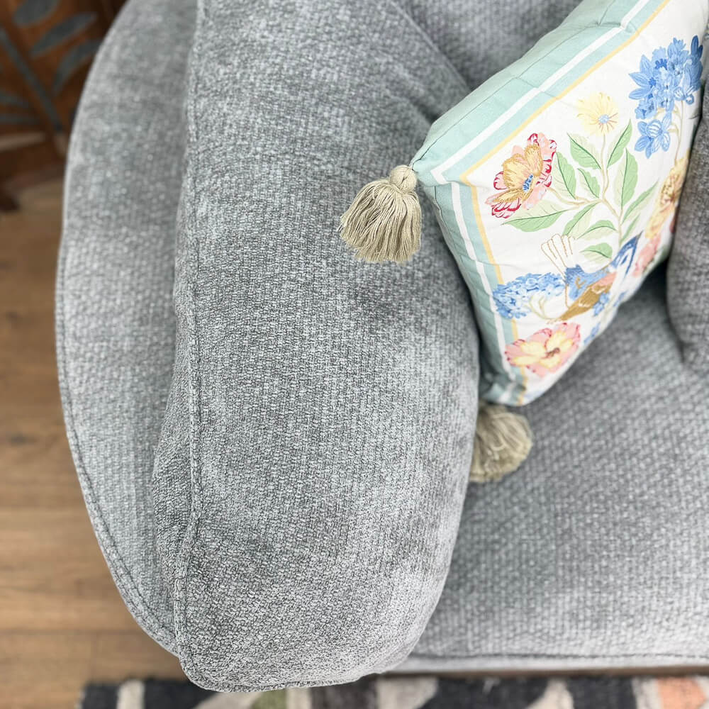 Close-up of Helena Grey Modular Corner Sofa cushion with a decorative throw pillow featuring a floral and bird pattern in pastel colors.