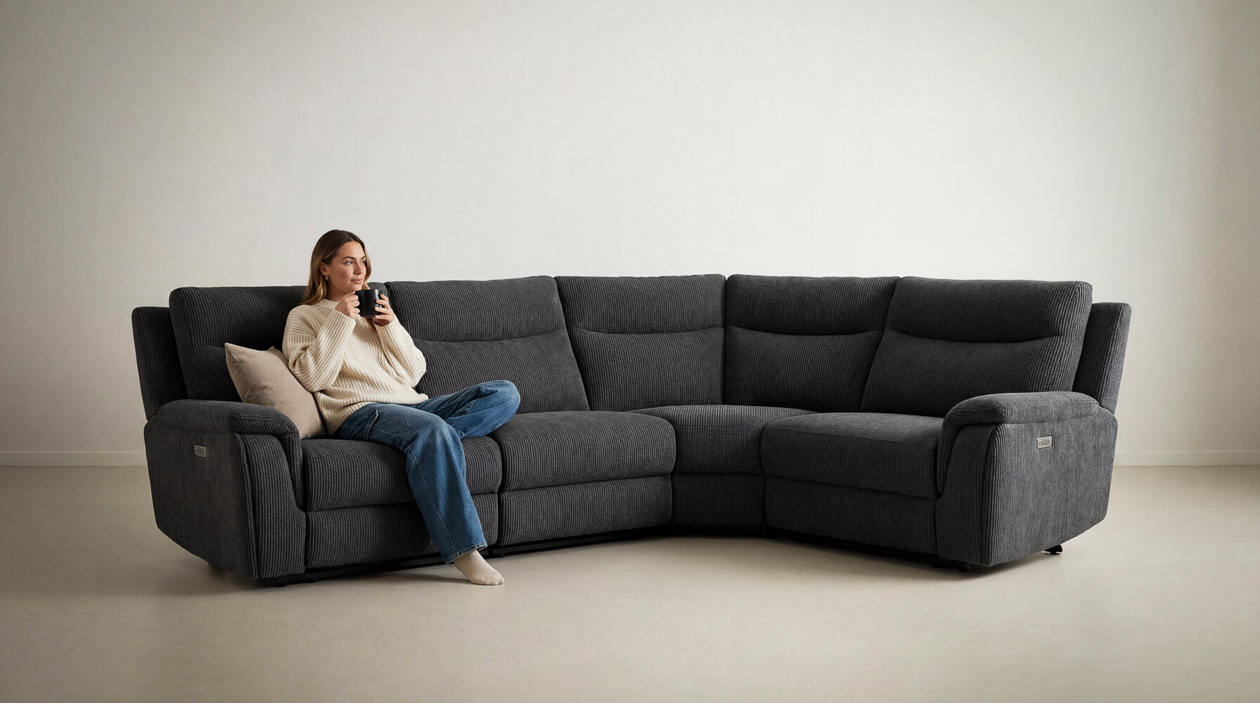 Women sitting on a large black maverick recliner corner sofa in a minimalistic room.