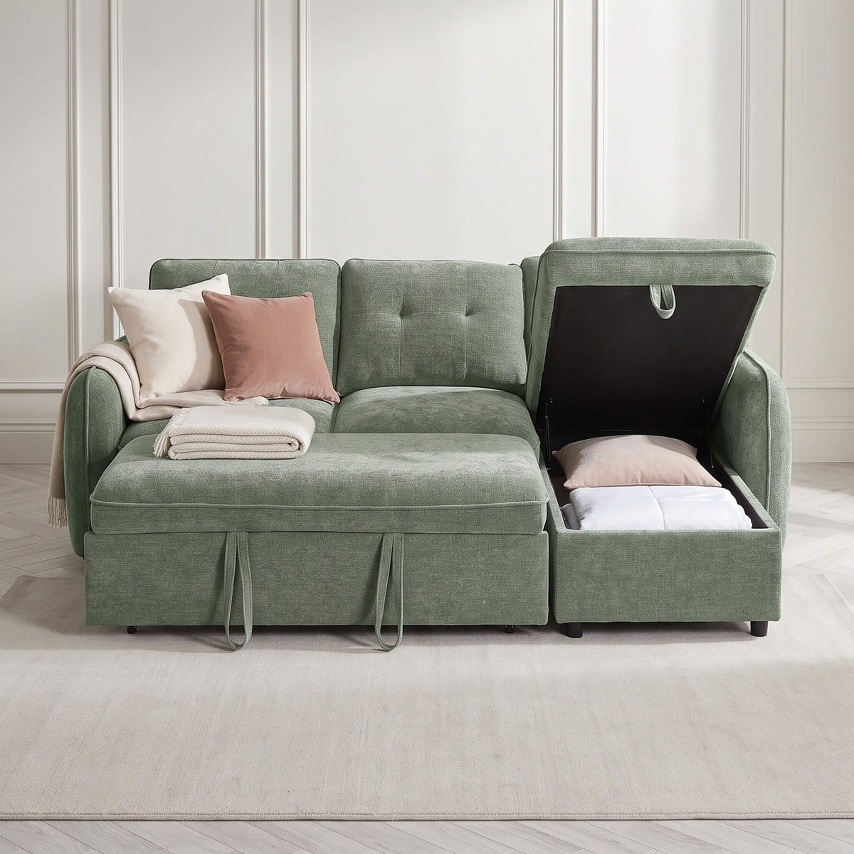Green sofa bed with back cushions and pull-out bed, styled with pillows and folded blankets