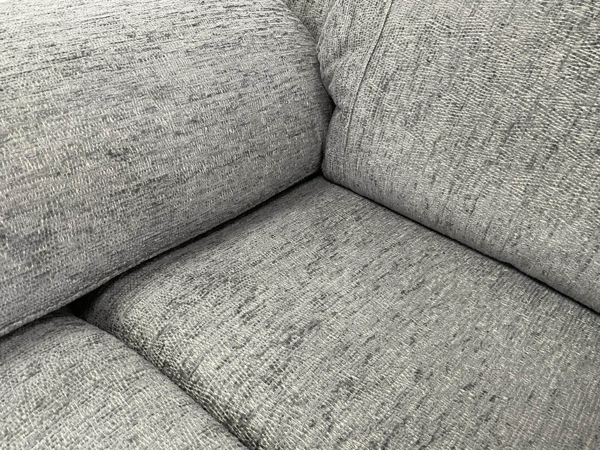 Grey recliner sofa interior view of padded seat and armrest upholstery texture.