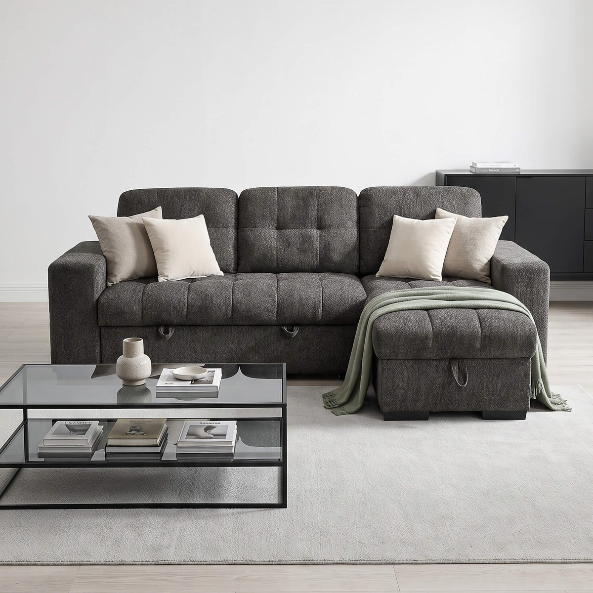 Gray corner sofa bed with two light pillows and folded blanket on chaise section