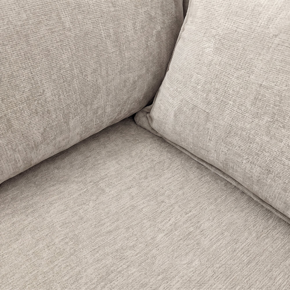 Beige sofa arm and seat corner with textured upholstery and seam detail