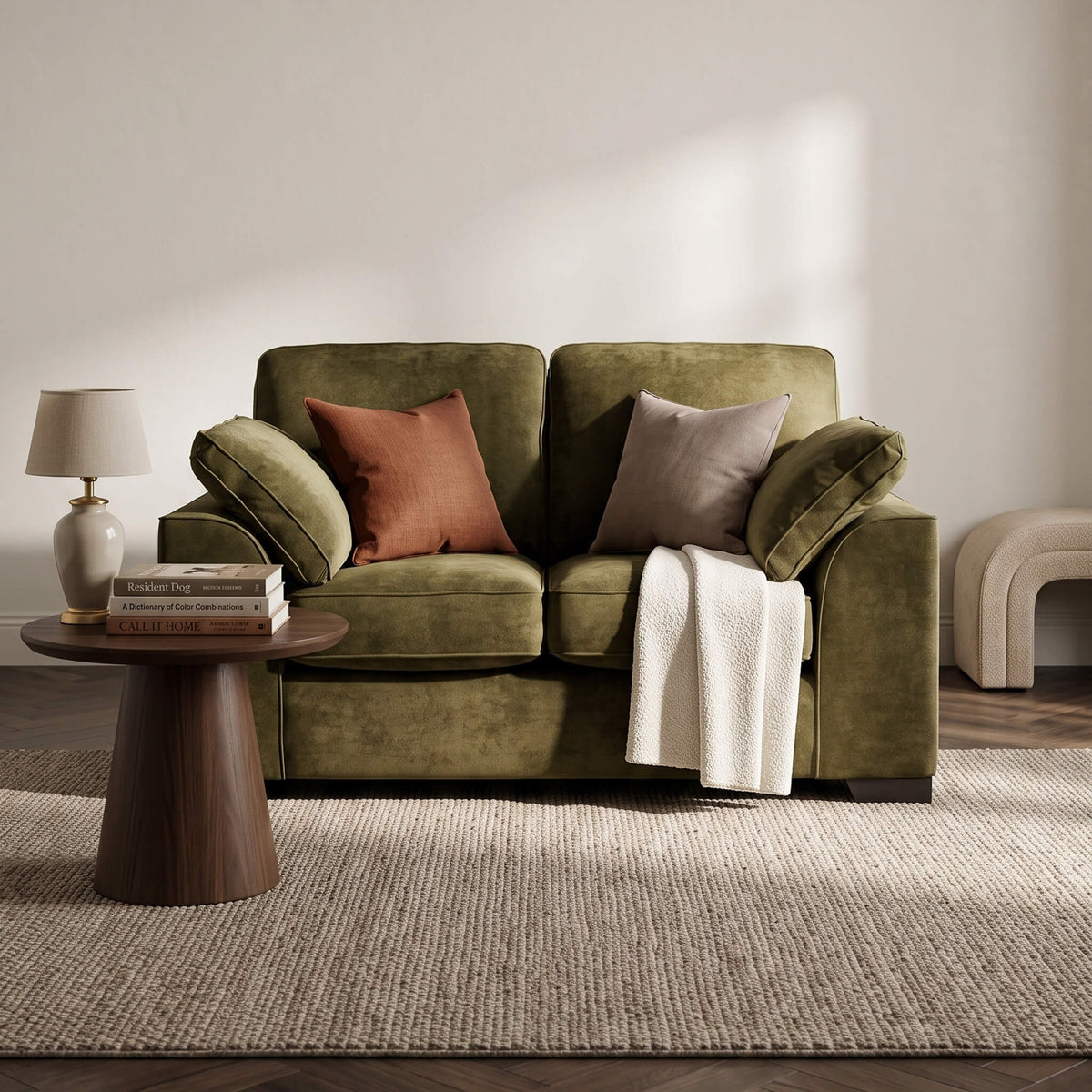 Olive green two-seat sofa with accent pillows and a white throw draped on the arm