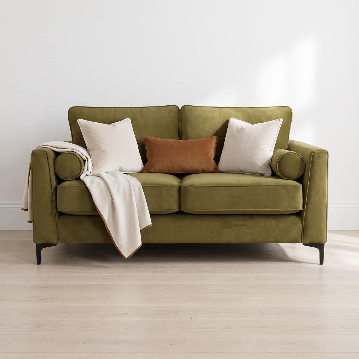 Adam Green 2-seater sofa with olive-green upholstery, styled with pillows and a throw blanket.