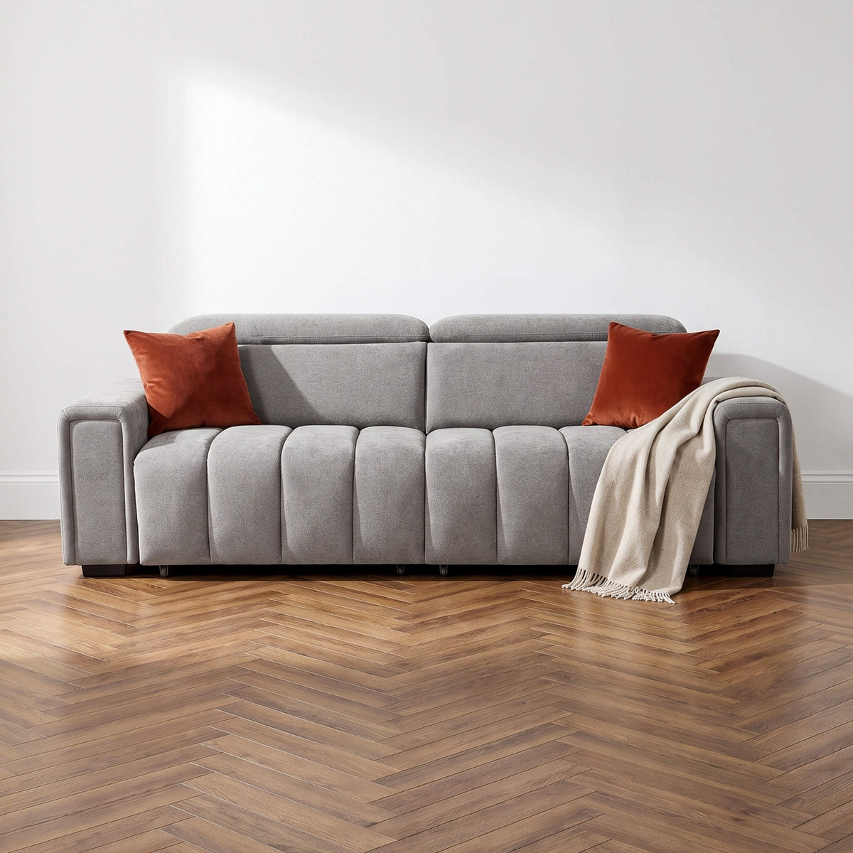Light grey 3-seater fabric sofa with two orange throw pillows and armrests