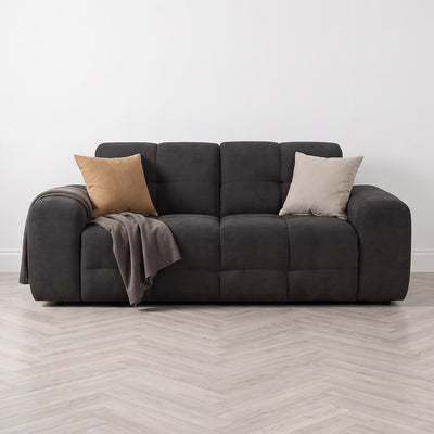 Black 3-seater sofa styled with two throw pillows and a draped blanket