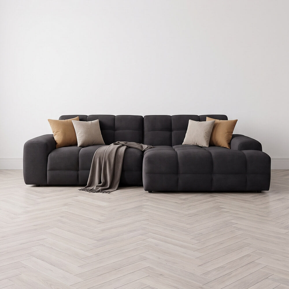 Dark right-corner sectional sofa with tufted seats, throw blanket, and accent pillows