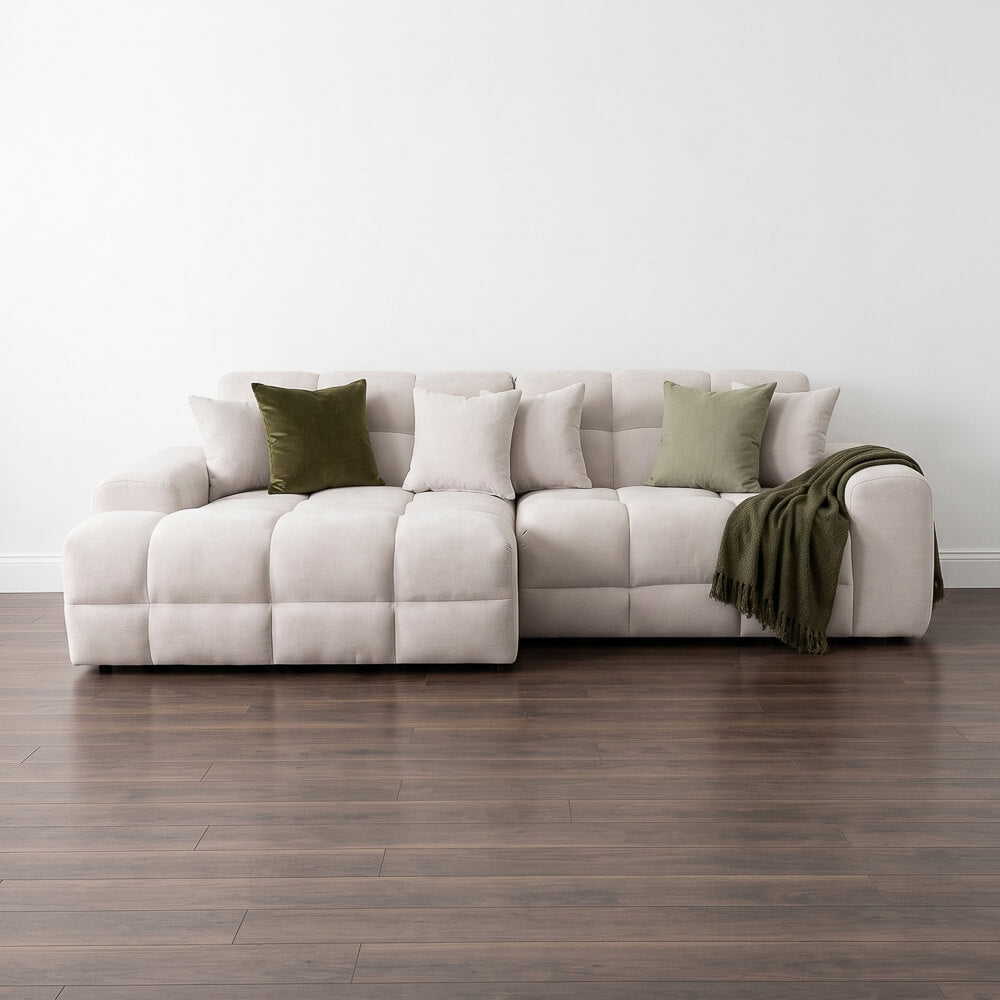 Left corner sofa with neutral cushions, olive throw blanket and accent pillows, light upholstery