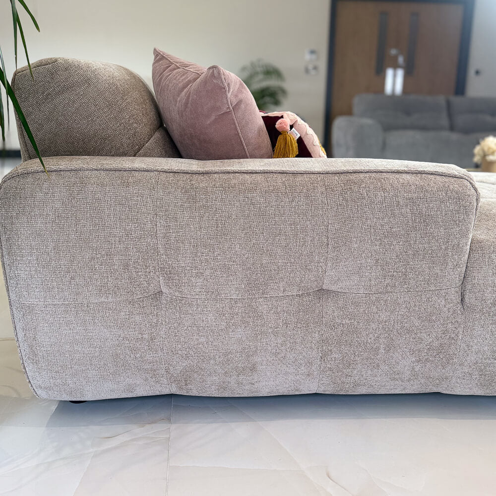 Close-up of beige corner sofa armrest and backrest with smooth fabric and stitched details.