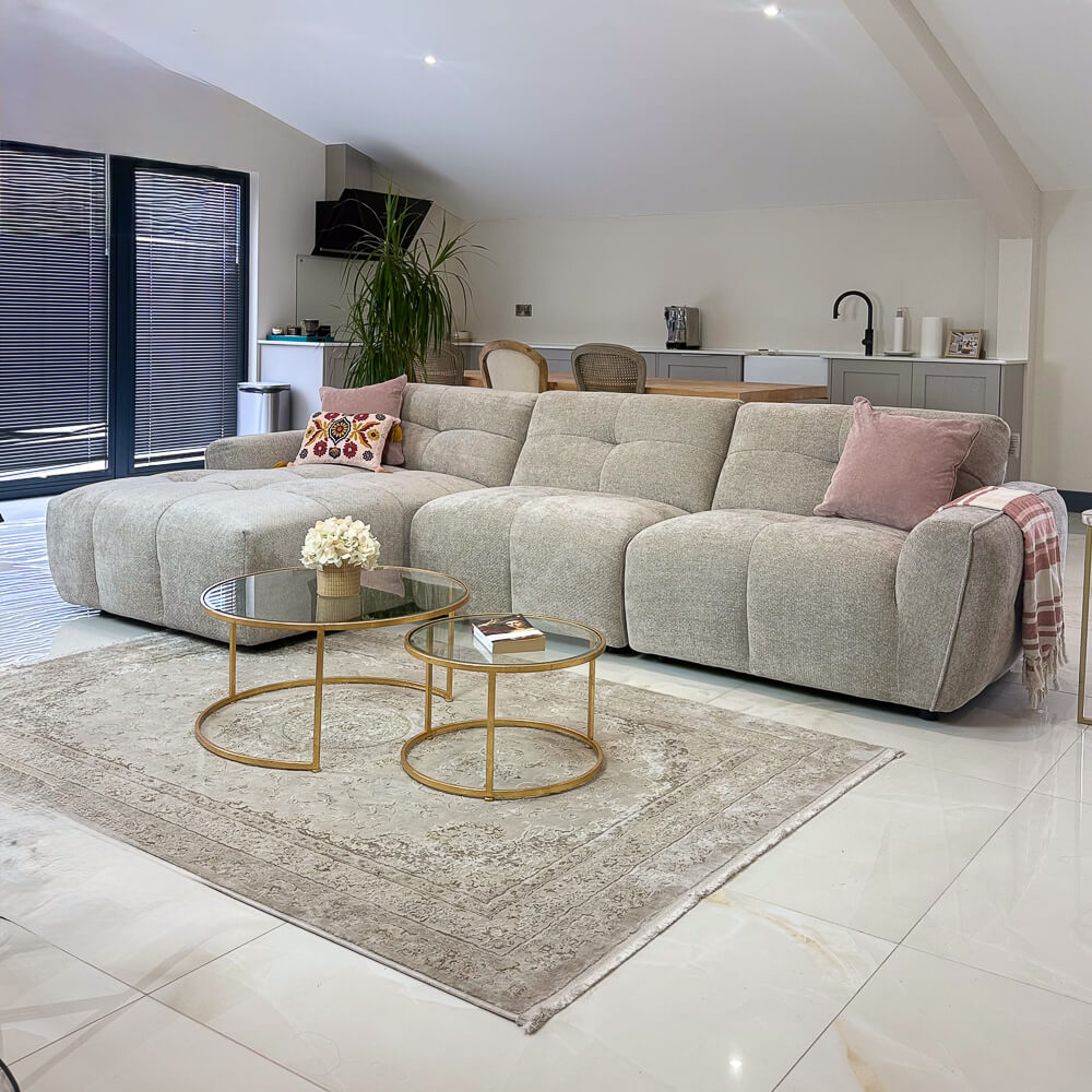 Beige left corner sofa with chaise, tufted seat and back cushions, fabric upholstery.