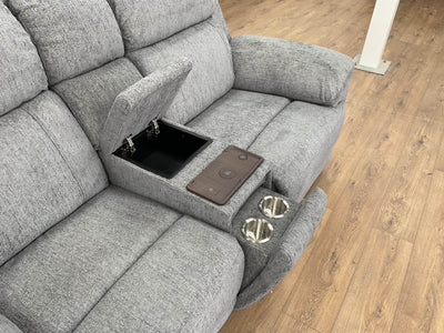 Grey power recliner sofa console with cupholders, tray, and storage opening in arm.