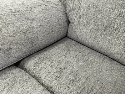 Grey recliner sofa interior view of padded seat and armrest upholstery texture.