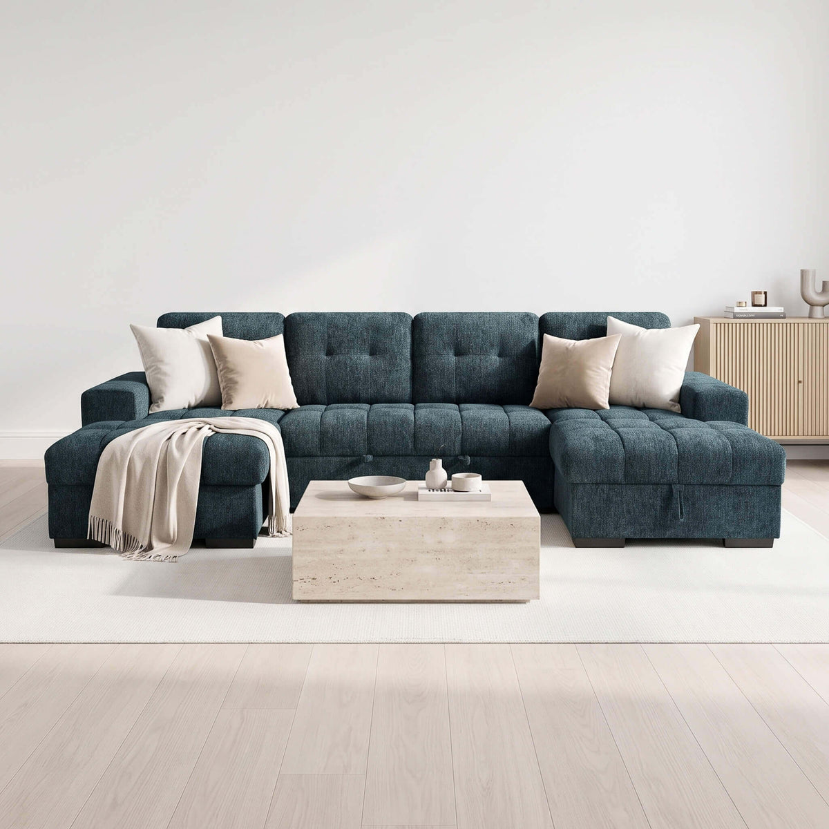 Teal U-shaped sofa bed with two white throw pillows and tufted backrest