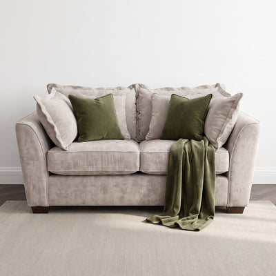 Beige 2-seater sofa with green throw blanket and two green accent pillows