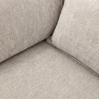 Beige sofa arm and seat corner with textured upholstery and seam detail