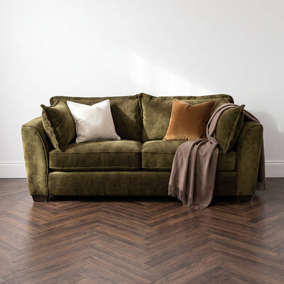 Dark green 3-seater sofa with throw blanket and white and brown accent pillows