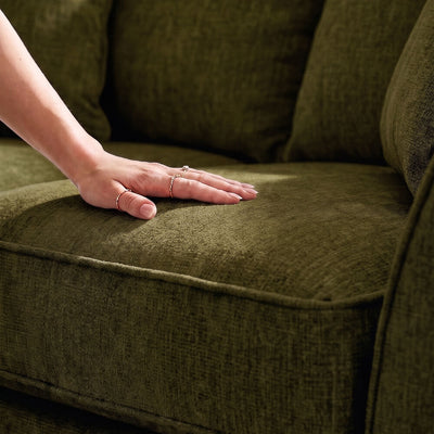 Dark green sofa cushion with hand resting on upholstered seat, showing textured fabric