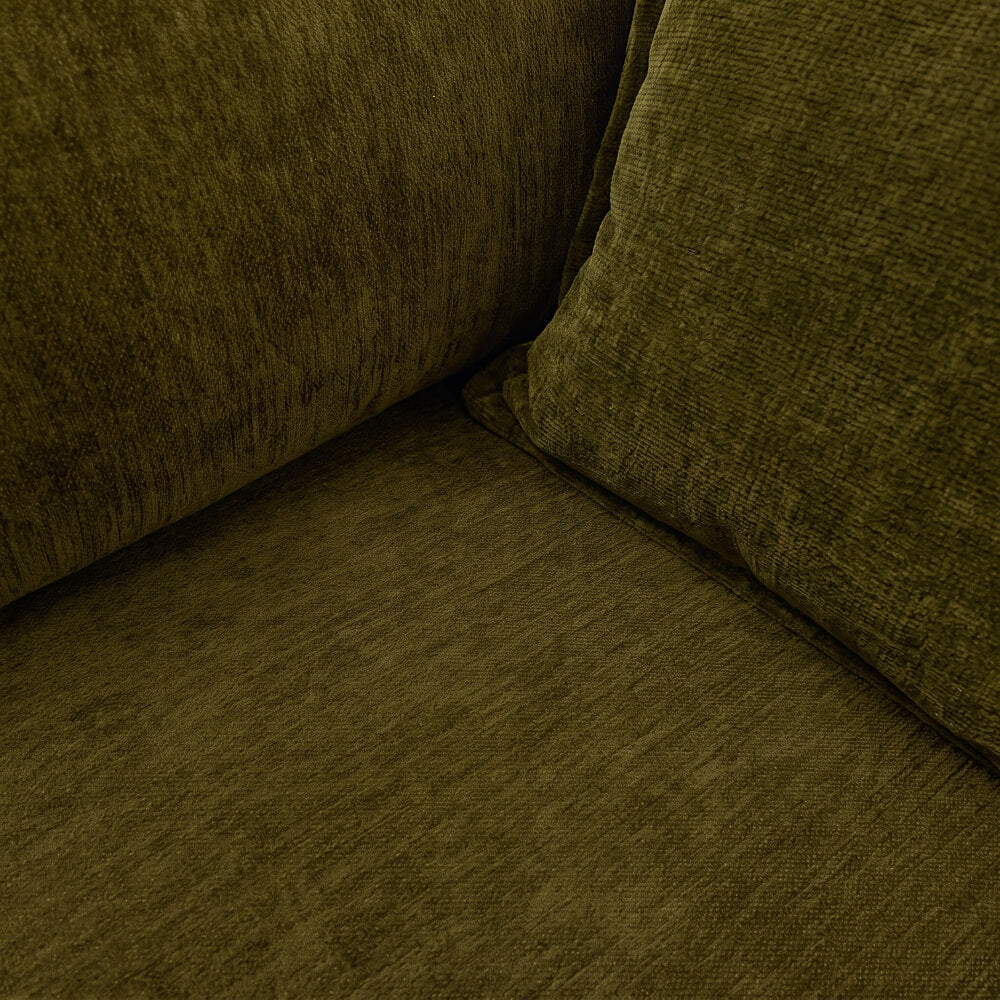Corner view of dark green velvet sofa seat and back, showing fabric texture