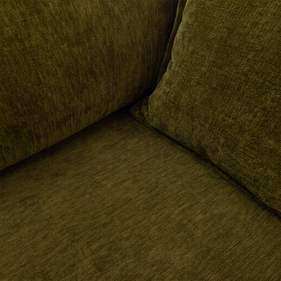 Corner view of dark green velvet sofa seat and back, showing fabric texture